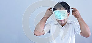 AsianÂ Man in medical maskÂ Coronavirus pandemic disease on grey background. COVID-19 virus from China epidemic outbreak to global